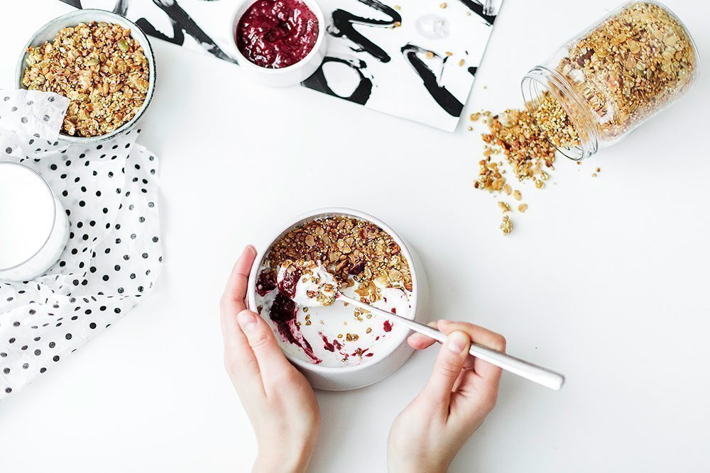 A bowl of delicious natural yoghurt with granola and fruit jam.