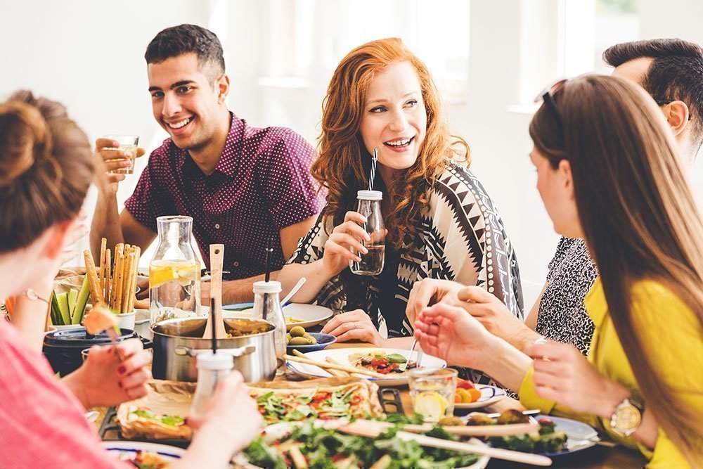 A group of friends enjoying a healthy buffet-style meal at a dinner table.